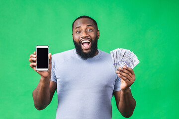 Happy winner! Young rich african american man in casual t-shirt holding money dollar bills and...