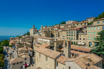 Obraz premium Aerial view of San Marino old town with old buildings and red roofs on the hill on a sunny day with clear sky