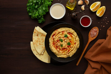 Classic chickpea hummus with tahini, olive oil, garlic and paprika, homemade, on a black background, top view, no people,