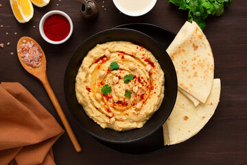 Classic chickpea hummus with tahini, olive oil, garlic and paprika, homemade, on a black background, top view, no people,