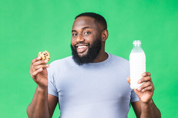 Portrait of young african american black man holding chocolate cookie biscuit and bottle of milk...
