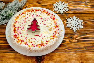 Christmas cake with white cream and a red gold  Christmas tree made of sprinkles. Homemade Christmas cake in red and gold flat lay copy space. Christmas food background top view