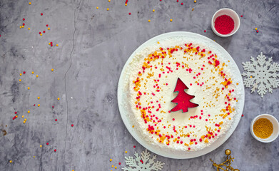 Christmas cake with white cream and a red gold  Christmas tree made of sprinkles. Homemade Christmas cake in red and gold flat lay copy space. Christmas food background top view