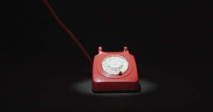 Hand picking up and hanging red vintage telephone
