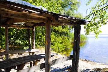 An old wooden home-made and handmade gazebo by the river. Wooden table. Recreation area in nature....