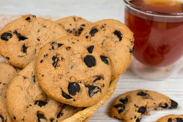 Chocolate cookies in a basket on the background of a glass cup of tea. Close-up.