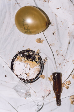 Sweet smashed birthday cake near balloons and glass bottles