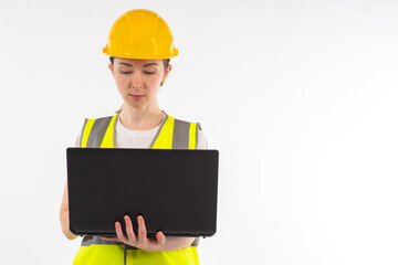 Woman builder with laptop. Girl engineer. Builder on white background. Engineer is designing something. Concept - she uses construction software. Engineer in yellow vest and hard hat.