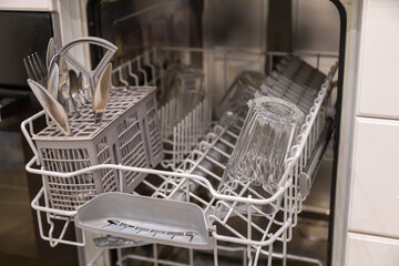 The dishwasher, the door is open. On the upper level there are dining accessories. Cleaning services. Cleaning of rooms. Restaurants, canteens.