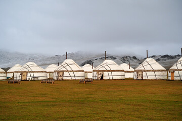 nomad houses-yurts on the background of of snowy mountains and gray sky. High quality photo