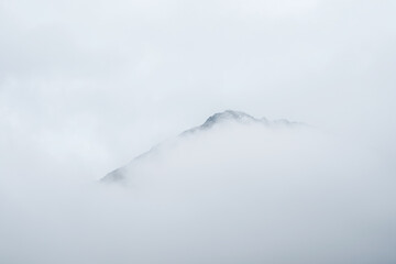 Soft focus. Wonderful minimalist landscape with big snowy mountain peaks above low clouds....
