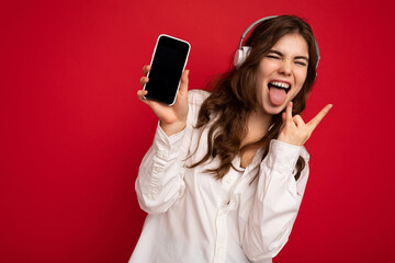 Attractive crazy positive young brunette curly woman wearing white shirt isolated on red background...