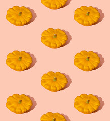 Creative pattern made of fresh pumpkins against light pink sun lit background. Minimal Autumn or Halloween celebration idea.