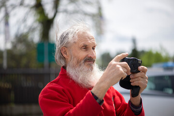 Close-up face portrait of bearded senior man photographer with old camera taking photo