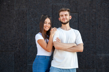 Emotions, gesture, expression and people concept - Happy couple Caucasian man and woman standing in white T-shirts and jeans and looking at the camera on a black background with copy space