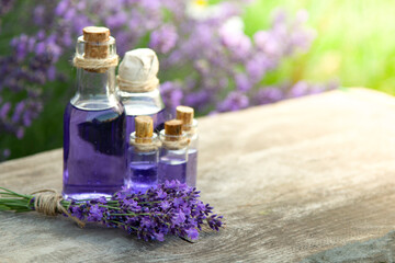 Fototapeta na wymiar Glass bottle of Lavender essential oil on wood table and flowers