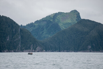 Fishing boat sailing in a lake surrounded by hills and mountains in Alaska