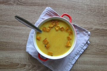 Bowl of vegan pumpkin and tofu curry soup on wooden table. Flat lay.