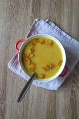 Bowl of vegan pumpkin and tofu curry soup on wooden table. Flat lay.