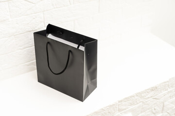 black paper bag with handles on a white background