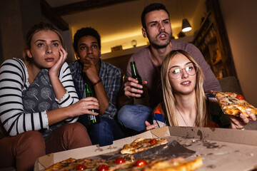 Best friends sitting at home watching  movie .Joying in tv show and eating pizza.	
