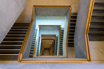 Contemporary concrete staircase with wooden handrail as viewed from the top floor