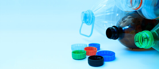 Plastic bottles and lids on a light background with space for text. The concept of separate sorting of plastic, rejection of plastic, production of plastic bottles