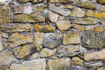 The rough textured surface of the wild stone wall. Background.