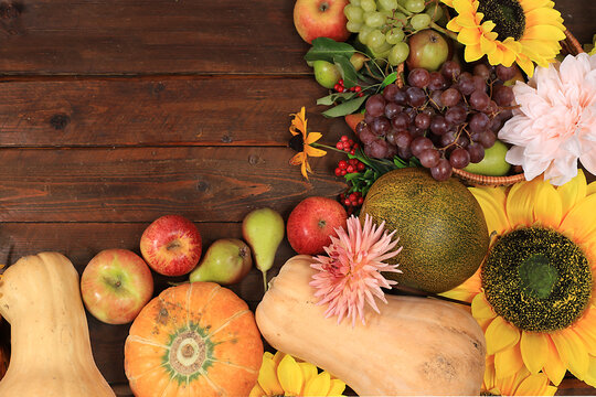 Happy Thanksgiving concept, autumn background with seasonal fall nature berries, pumpkins, melons, apples, grapes and flowers on wooden background, top view, copy space, flat lay.