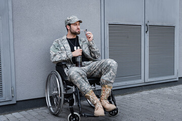 disabled veteran in wheelchair lighting cigarette and holding bottle of alcohol outdoors