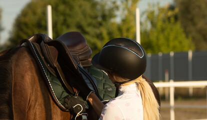 Young woman preparing to become a riding instructor taking care and talking to a horse.