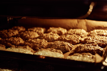 Baking tray with chip oatmeal cookies in oven. Homemade dessert. Culinary recipe with oat flakes. Useful confection. Diet bakery. Low calories. Hot oven. Concept of cozy home. Fresh sweet home bake