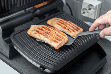 The chef prepares trout on an electric grill. Healthy food. Chef's hand. Homemade food. Photo