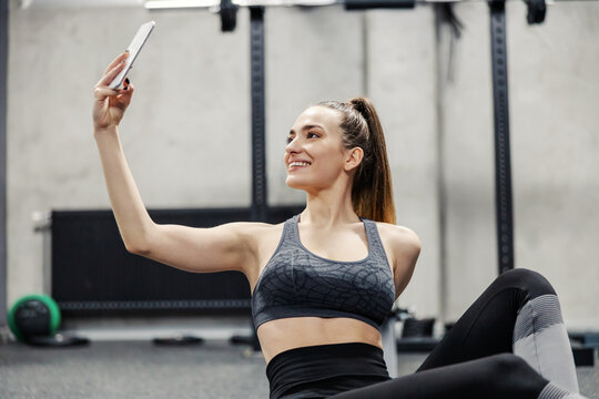 Fitness and social networks. Close up photo of beautiful female in sportswear takes photos of herself during training. She posts photos and videos from the training on social networks. Sports bra