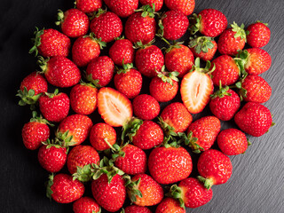 A lot of red ripe and fresh strawberries on black slate background
