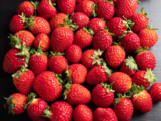 A lot of red ripe and fresh strawberries on black slate background