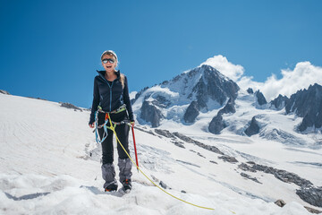 Happy cheerful sincerely laughing young female portrait in climbing harness, crampons, sunglasses,...