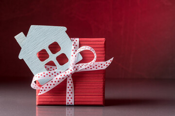Red gift box and house model over red background
