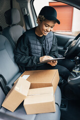 Female courier preparing packages for transportation while sitting on driver's seat