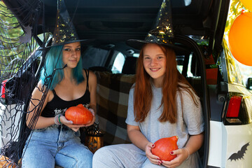 Two girls generation Z celebrating Halloween car trunk. Autumn holidays