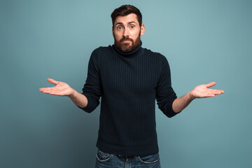 I don't know. Portrait of confused handsome bearded young man standing with raised arms and looking...