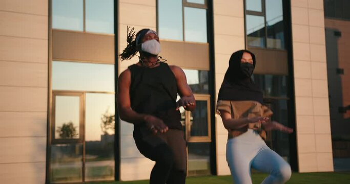 Black man and Muslim Asian woman with masks jump at training