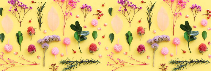 Top view image of pink, purple and green flowers composition over pastel yellow background .Flat lay