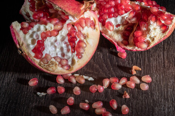 Ripe Pomegranate Cut Open on a Dark Background, Pomegranate Seeds Placed Next to It.