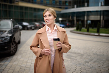 Fototapeta premium Portrait of a beautiful businesswoman with coffee near the business center