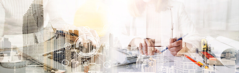 Two colleagues discussing data working and tablet, laptop with on on architectural project at construction site at desk in office