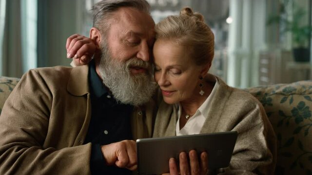 Old aged tender couple looking tablet computer together in luxury home