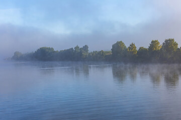 Scenic river landscape with green trees in early autumn