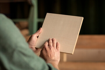 Checking a piece of wood, MDF with wooden veneer material in a woodworking workshop with a designer...