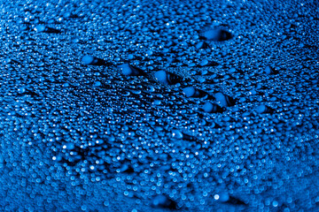 Colourful abstract background with water drops illuminated with blue LED light.